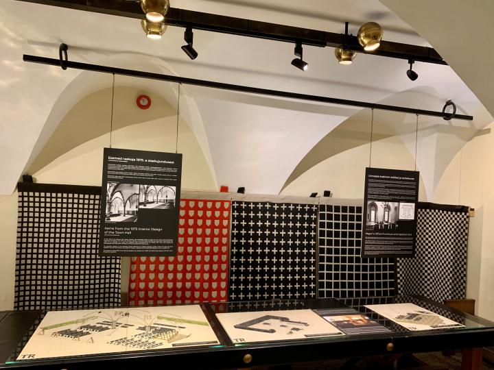 Näituse vaade. Laual Leila Pärtelpoja sisekujunduse kavandid 1973-1975, taustal 1975 kodanikesaali jaoks kootud seinavaibad (Anu Raud, Valve Ilveste)